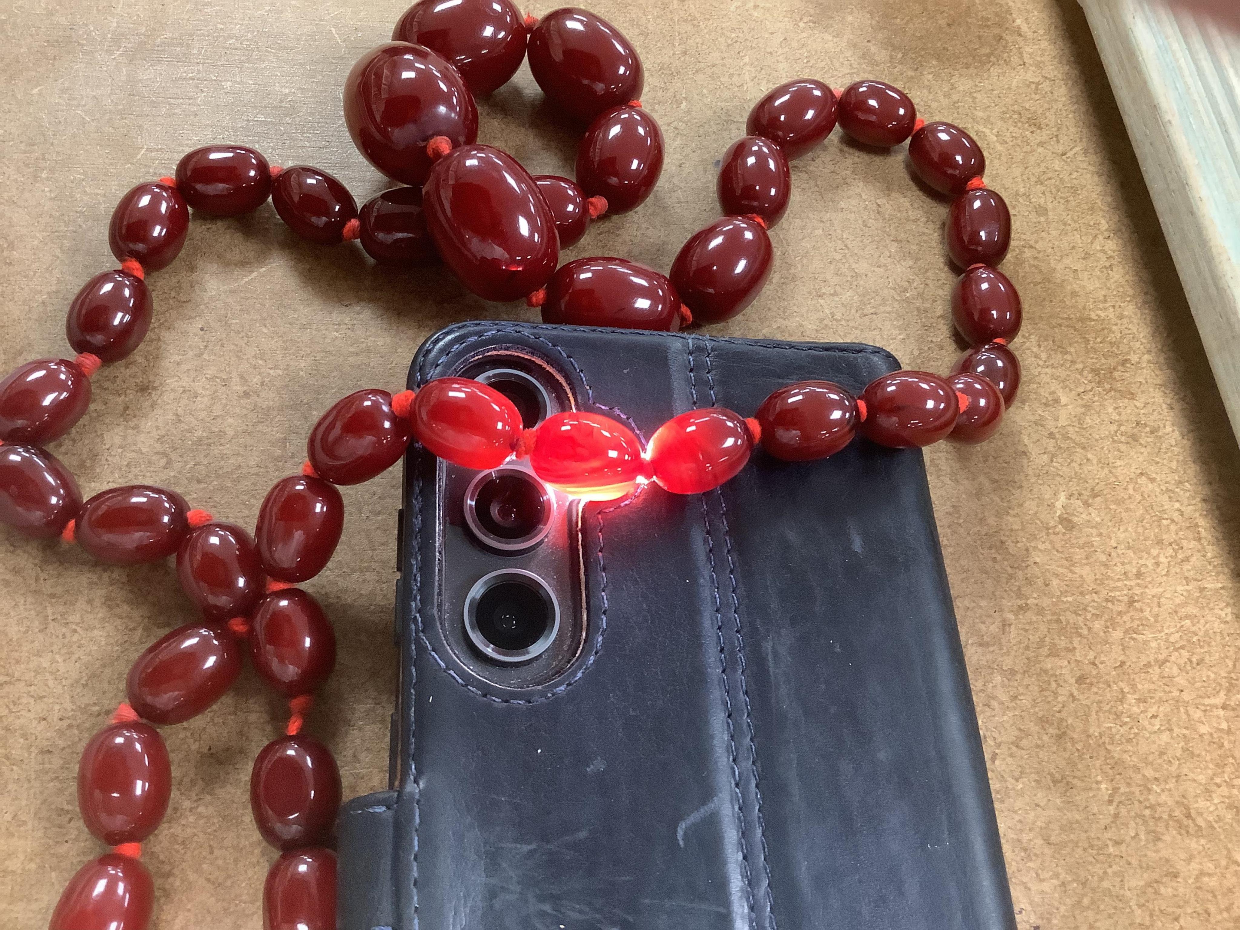 A single strand graduated simulated oval cherry amber bead necklace, 72cm, gross weight 100 grams.
